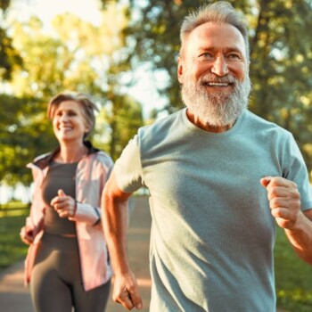 A couple smiling and running outdoors.