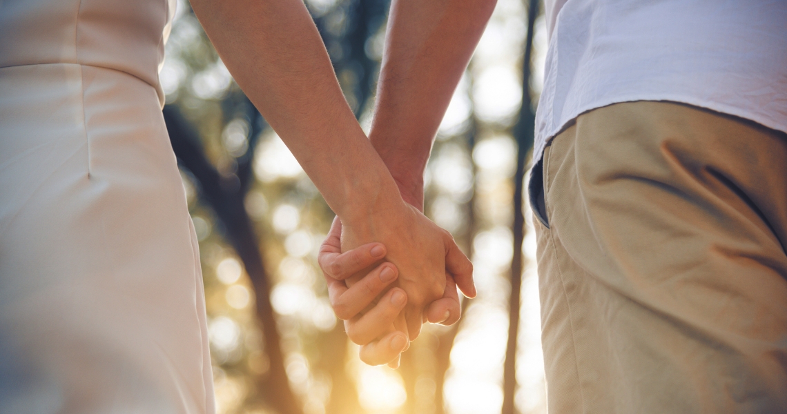 A couple holding hands in the forest.