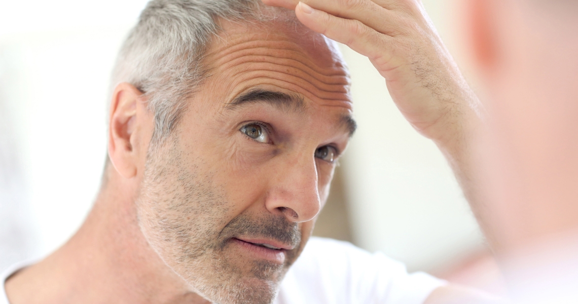Older man examining his thinning hair.