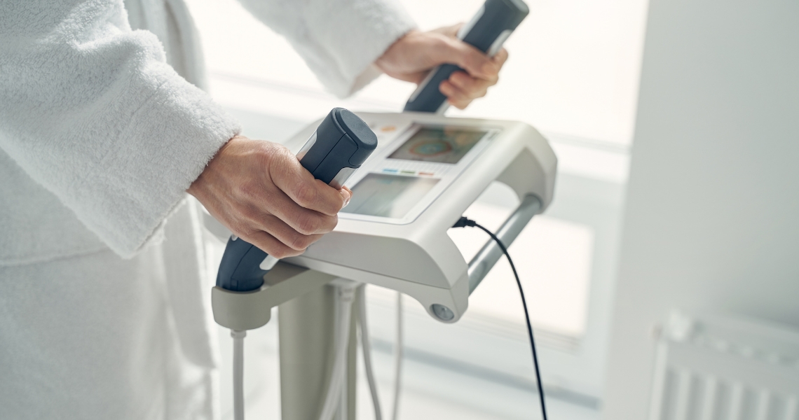 A person in a white robe using a body composition measurer.