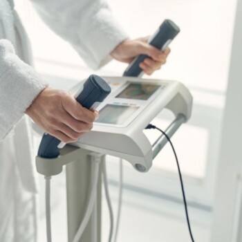 A person in a white robe using a body composition measurer.