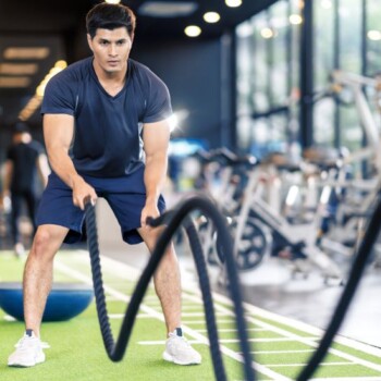 A man in the gym using gym ropes to workout.