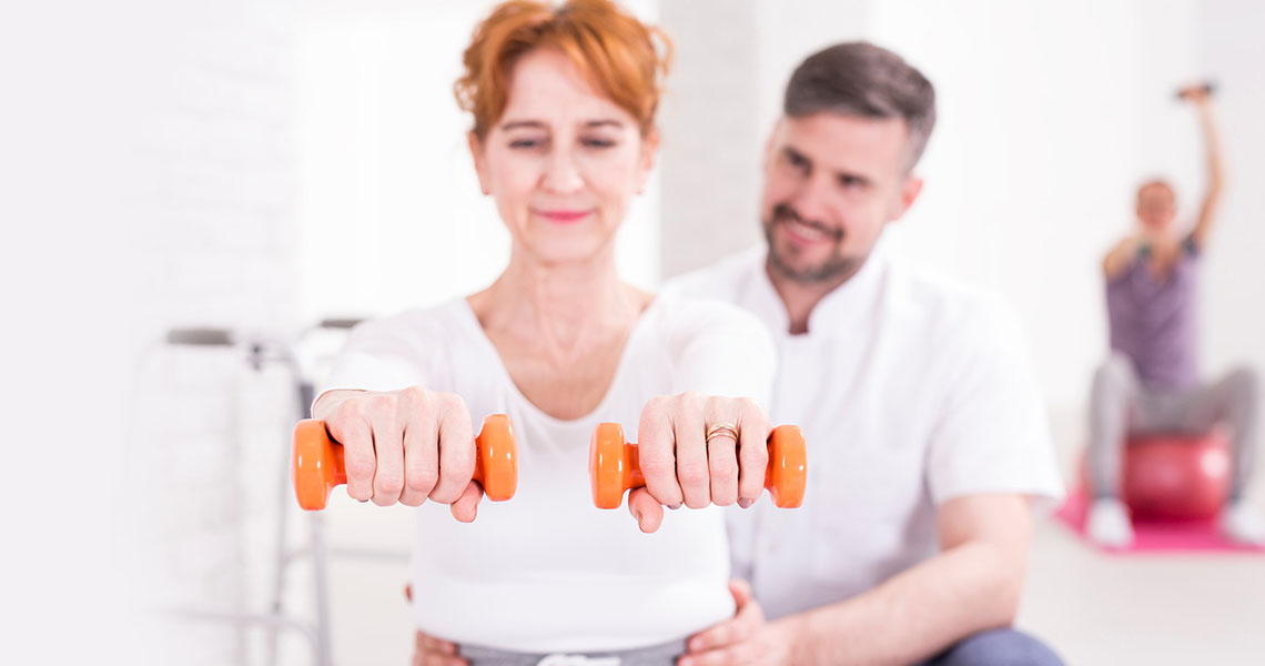 White background with woman holding hand weights and doctor behind her.