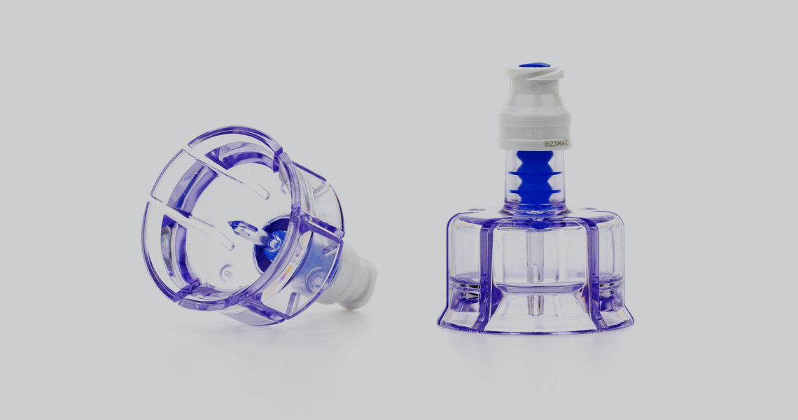 Two angles of a clear vial adapter with a light gray background.