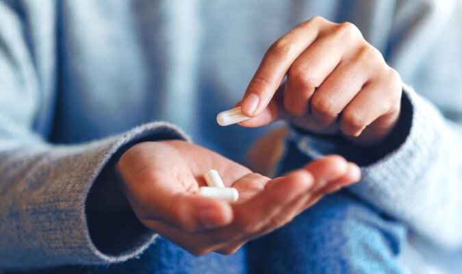 A set of hands holding and examining capsules.