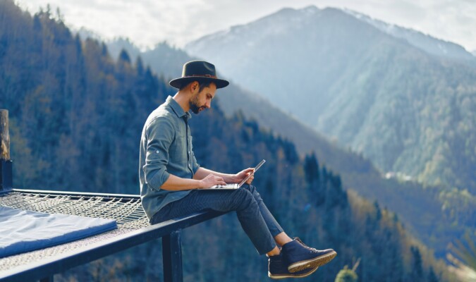 A man sitting on a hammock with the mountains in the background.