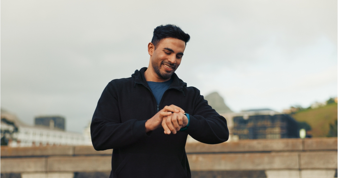 A man outdoors checking his watch.