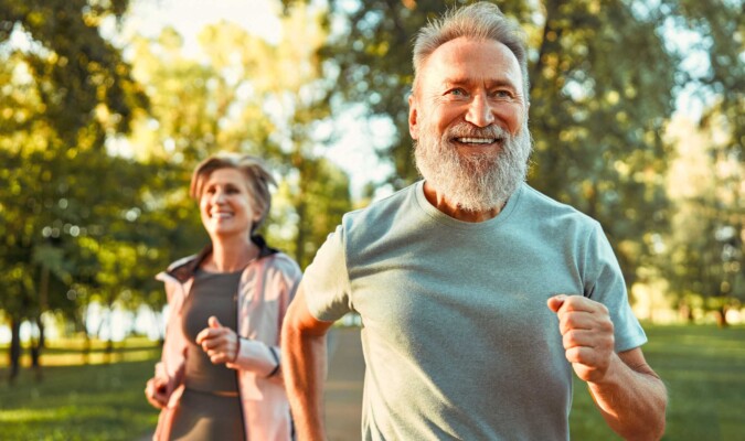 A couple smiling and running outdoors.