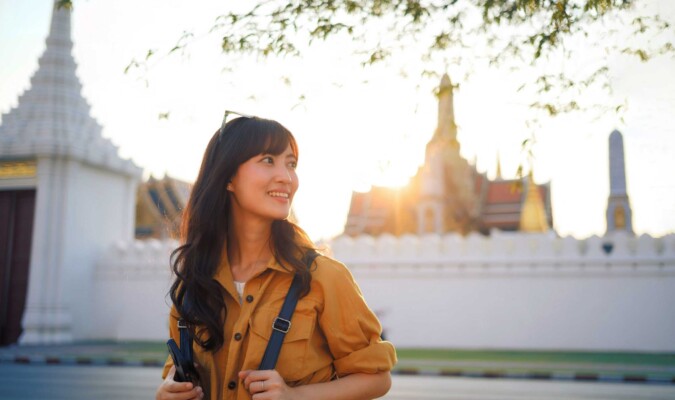 A woman outside with her backpack and buildings in the background.