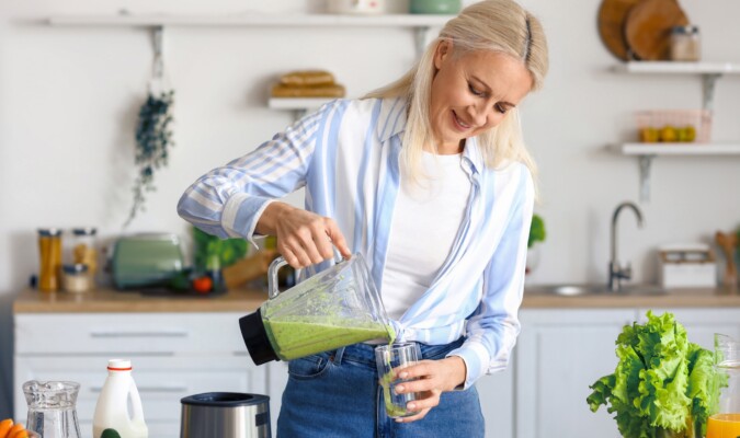 A woman making a green smoothing in the kitchen.