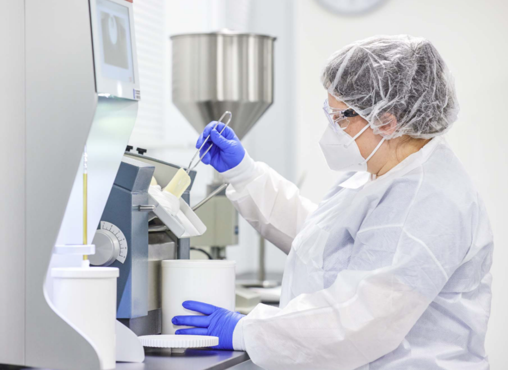 A worker in a white clean suit working on a machine.