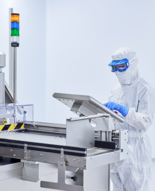 A worker in a white clean suit at a machine