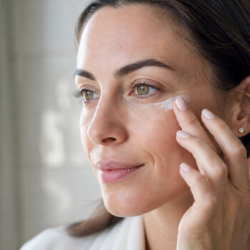 woman completing her skincare routine by applying cream to face