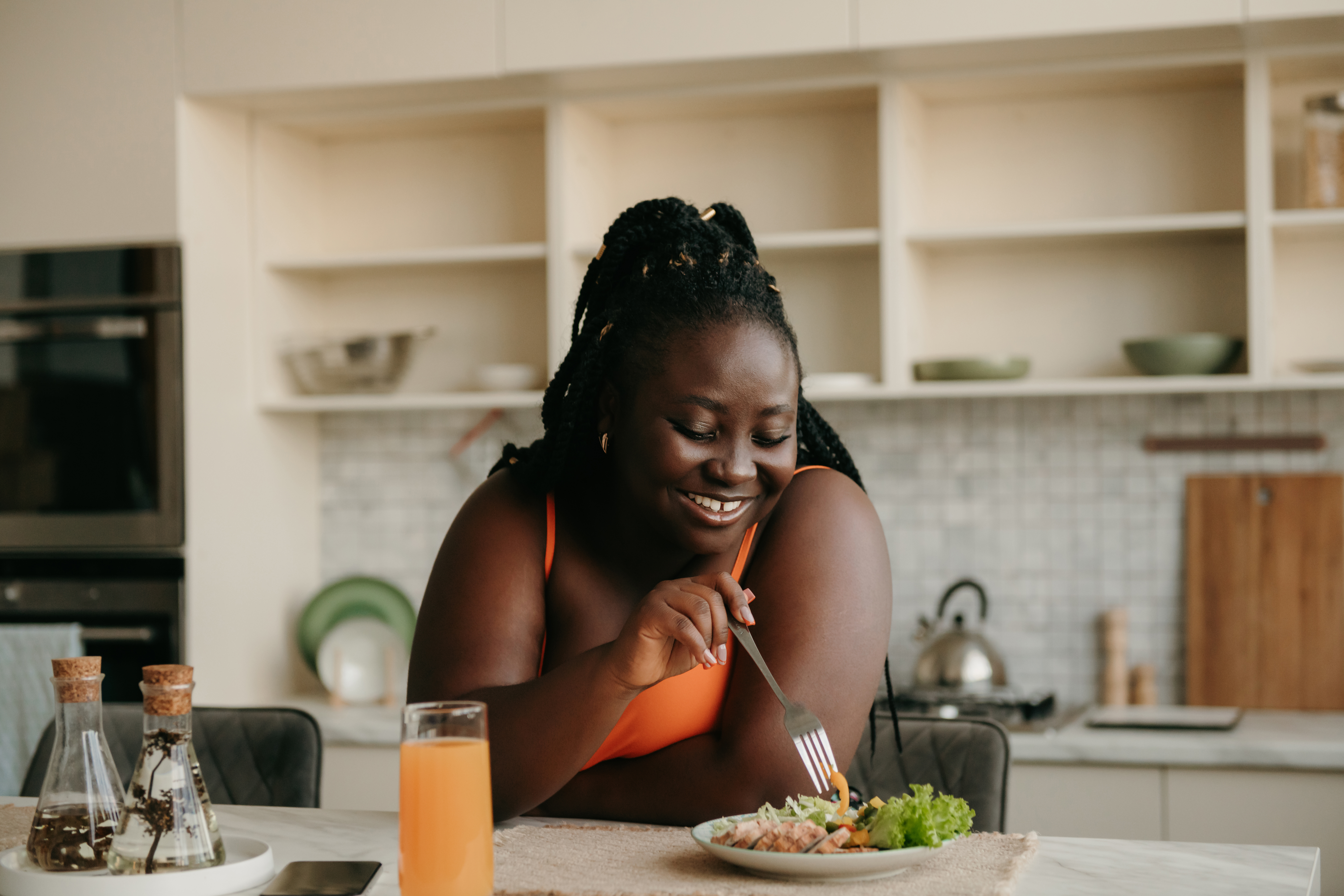 woman eating on kitchen counter with a glass of OJ next to the plate