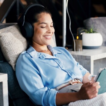 Happy woman, tablet and headphones with IV drip for healthcare, infusion treatment and streaming video.