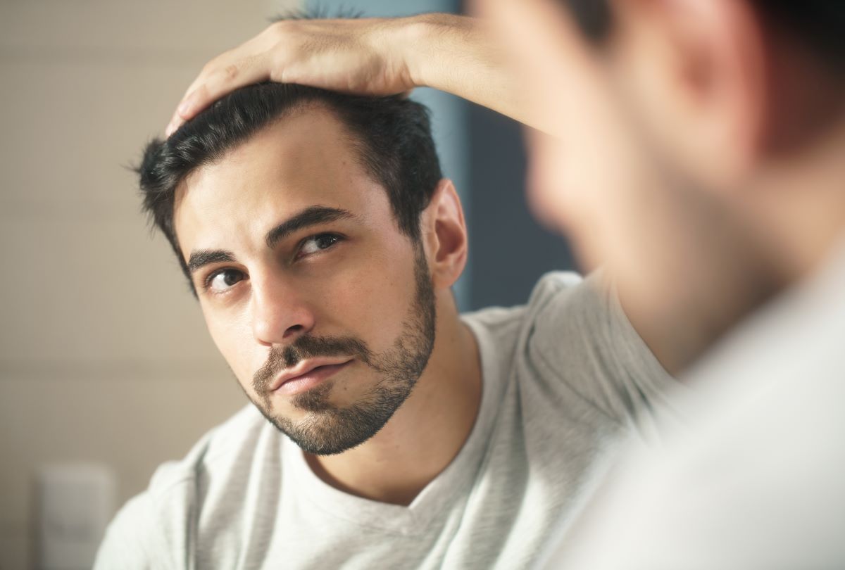 A man examining his hair in the mirror