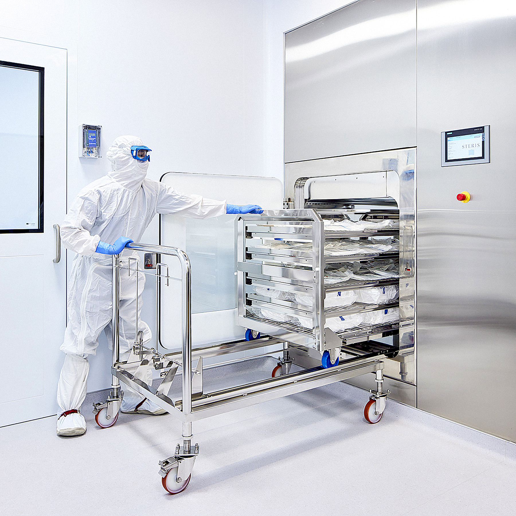 A worker in a clean white suit pulling trays from a machine